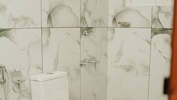 Ein Badezimmer mit Toilette, Dusche und einem kleinen Fenster.