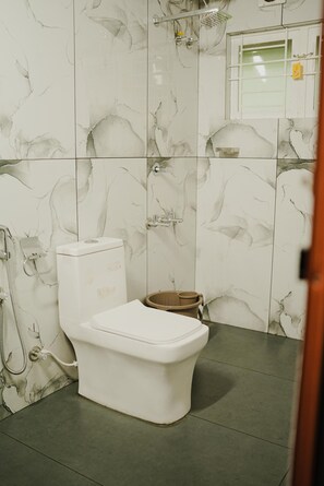 A bathroom with a toilet, a shower, and a small window.