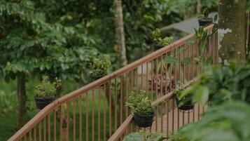 A wooden staircase with metal railings, surrounded by lush greenery and trees.