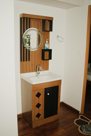 A bathroom with a wooden vanity, a mirror, a sink, and a towel rack.