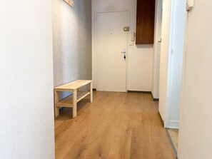 A hallway with a wooden bench, a white door, and a wooden cabinet. - Hostcare - Le Fredet | L’instant grenoblois (Grenoble)