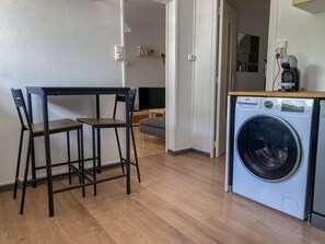 Ett kompakt bostadsutrymme med en matplats, en soffa, en tvättmaskin och en tv.