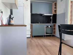A compact kitchen with a built-in oven, a microwave, and a gas stove. - Hostcare - Le Fredet | L’instant grenoblois (Grenoble)