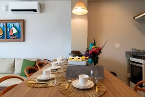 Ein Essbereich mit einem Holztisch, gedeckt für vier Personen, einer Blumenvase und einem Gemälde an der Wand.