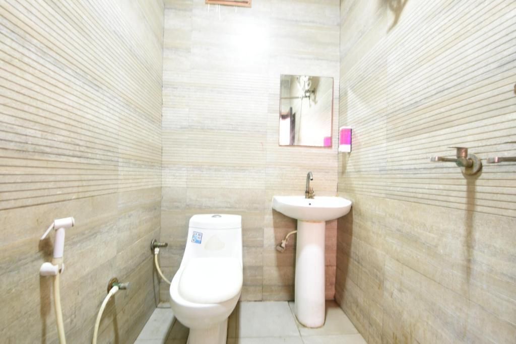 Een kleine betegelde badkamer met toilet, wastafel en een spiegel.