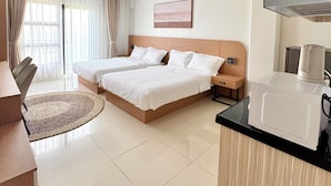 Habitación de hotel con cama doble, una mesa redonda, kitchenette y un ventanal con cortinas.
