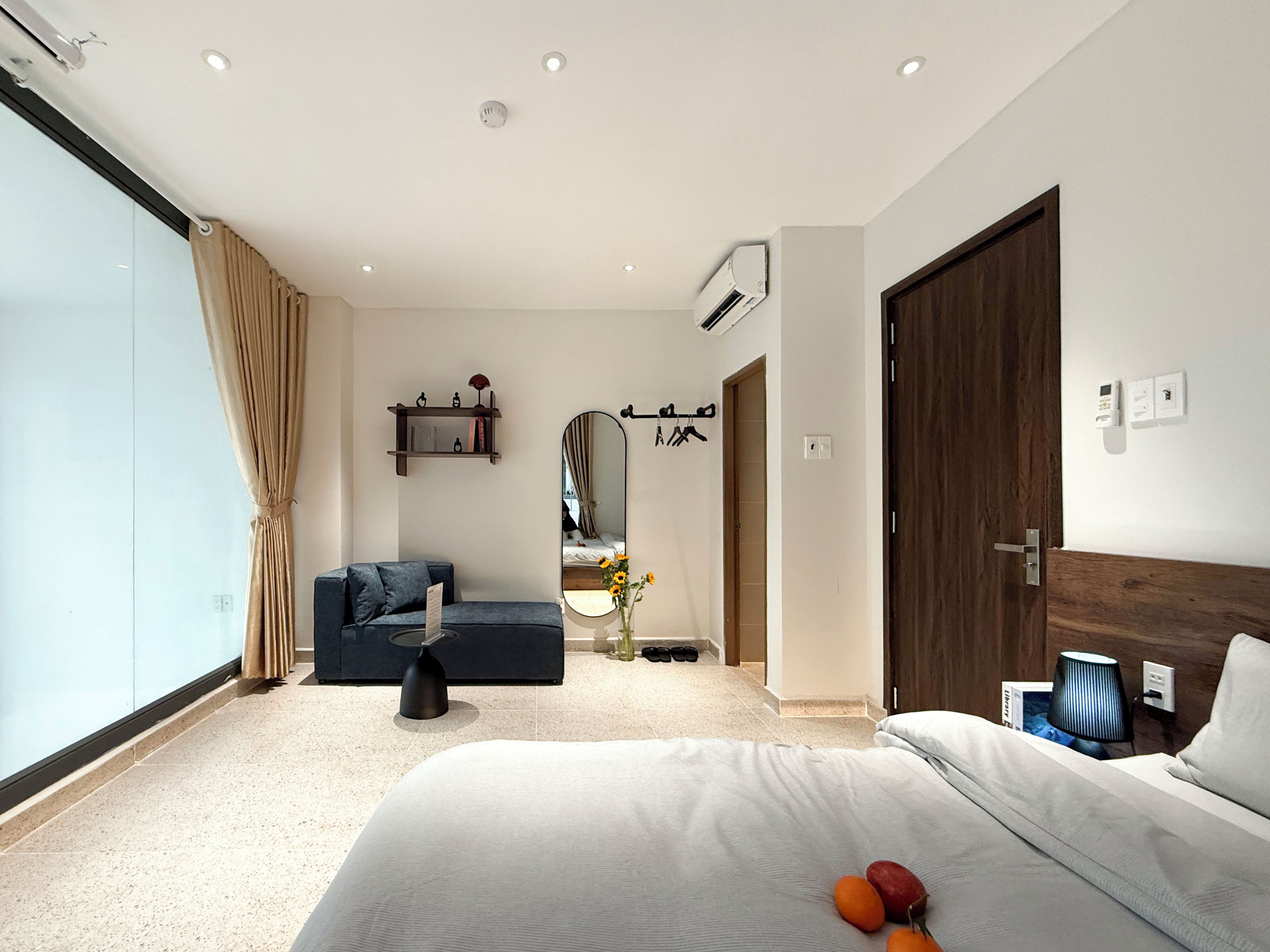 A modern hotel room with a large bed, a sofa, a mirror, and a wardrobe.