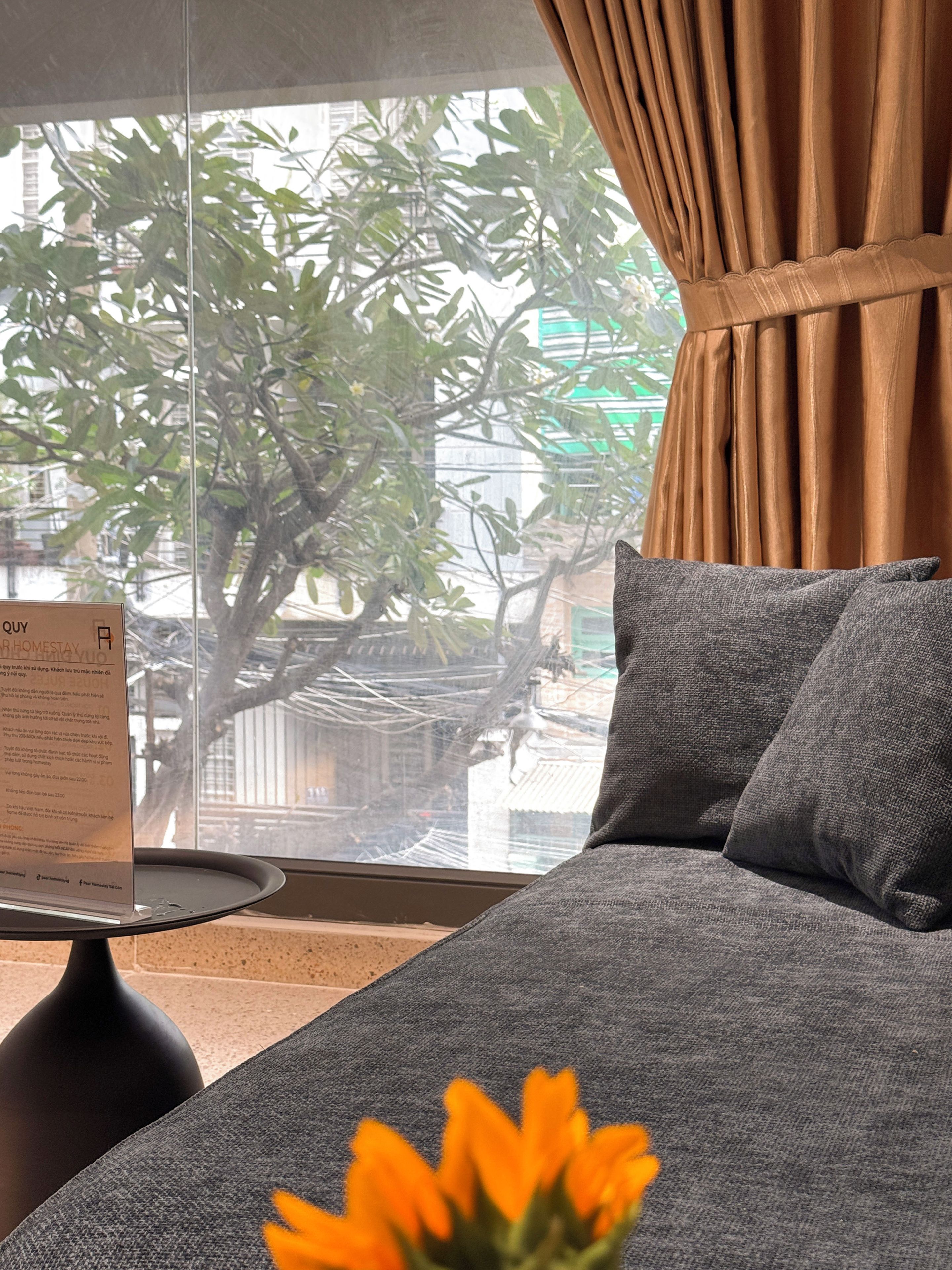 A room with a bed, a window with curtains, a small table, and a sign.
