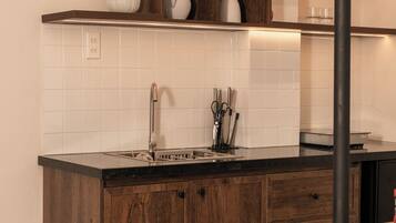 A kitchen with wooden cabinets, a white tiled backsplash, and a round dining table with stools.