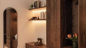 Ein modernes Wohnzimmer mit einem Holzkabinett, einer eingebauten Ablage, einem Spiegel und einer Vase mit Blumen.