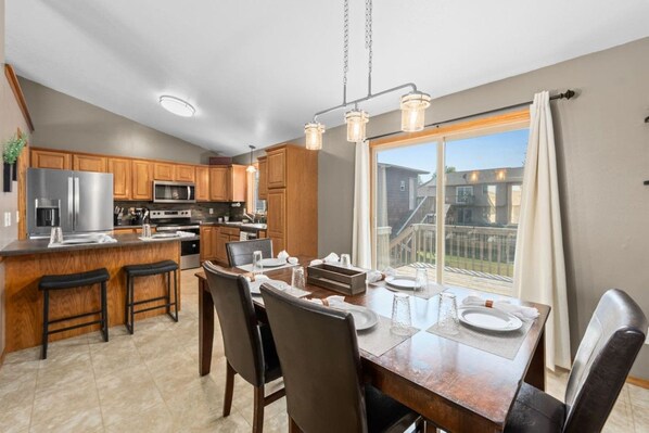 A modern kitchen with wooden cabinets, stainless steel appliances, and a dining area with a large table and chairs.