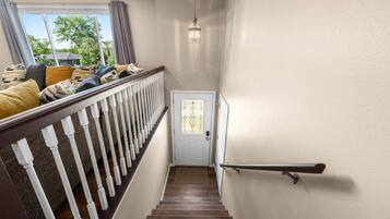 Eine Treppe mit weißer Geländer, eine Tür mit Fensterteil und eine hängende Leuchte.