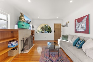 Una sala de estar moderna con chimenea, televisor grande, sofá y alfombra colorida.