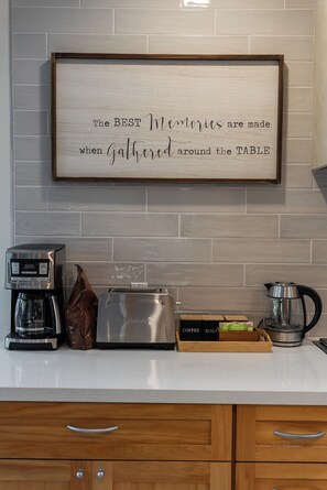 A kitchen with a coffee maker, toaster, and kettle on the counter, and a framed sign on the wall. - SAN DIEGO SPA VILLA - Cozy Yard, Firepit, Rec Room (San Diego)