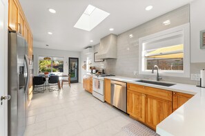 A modern kitchen with wooden cabinets, stainless steel appliances, and a large window. - SAN DIEGO SPA VILLA - Cozy Yard, Firepit, Rec Room (San Diego)