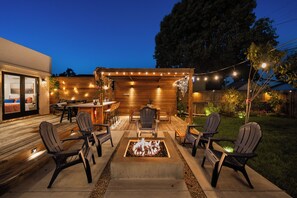 An outdoor patio area with a fire pit, seating, and string lights. - SAN DIEGO SPA VILLA - Cozy Yard, Firepit, Rec Room (San Diego)