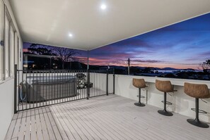 A balcony with a view of a sunset, a barbecue grill, and three bar stools. - The Bunkhouse - Bicheno Accommodation (Bicheno)
