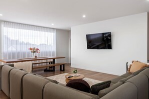 A modern living room with a sofa, a coffee table, a bench, and a TV mounted on the wall.