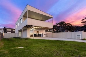 A modern two-story house with a flat roof, large windows, and an attached garage.