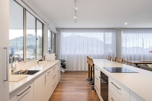A modern kitchen with a large island, bar stools, and a view of the city through large windows.