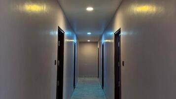Un pasillo con suelo de mármol y puertas a ambos lados, que conduce a una habitación.