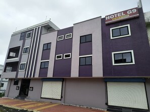 Un edificio de hotel de varios pisos con un letrero que indica 'HOTEL G9 AC NON AC ROOMS'.