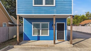 Een woongebouw met twee verdiepingen, een blauwe gevel, een voordeur en een klein portaal.