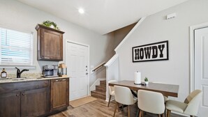 Una cocina moderna con armarios de madera, una cafetera y un comedor con mesa y sillas.