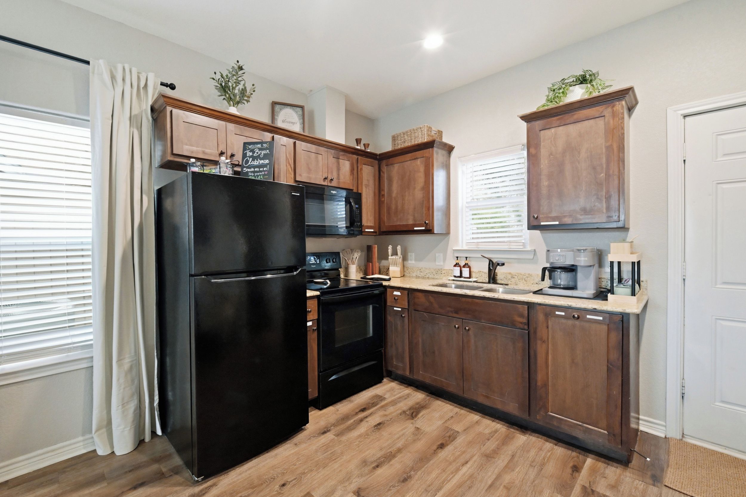A kitchen with wooden cabinets, a black refrigerator, a microwave, and a coffee maker.