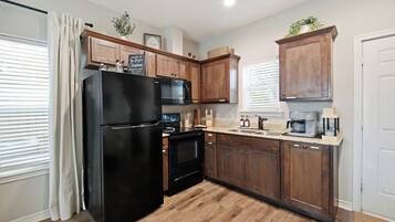 A kitchen with wooden cabinets, a black refrigerator, a microwave, and a coffee maker.
