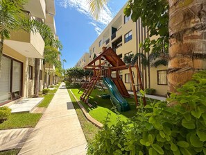 A residential building with a playground featuring a slide and climbing structures. - Relax at Oceanna | Rooftop, Jacuzzi, and 3 Pools (Mazatlán)