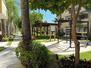 A courtyard with a pergola, trees, and a pathway. - Relax at Oceanna | Rooftop, Jacuzzi, and 3 Pools (Mazatlán)