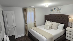 A bedroom with a bed, curtains, a bedside table, and wall art. - Catskills Stone Getaway - 6BR, Sleeps 14, Game Room, Firepit, Near Skiing (Purling)
