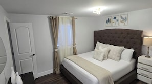 A bedroom with a bed, curtains, a bedside table, and wall art. - Catskills Stone Getaway - 6BR, Sleeps 14, Game Room, Firepit, Near Skiing (Purling)