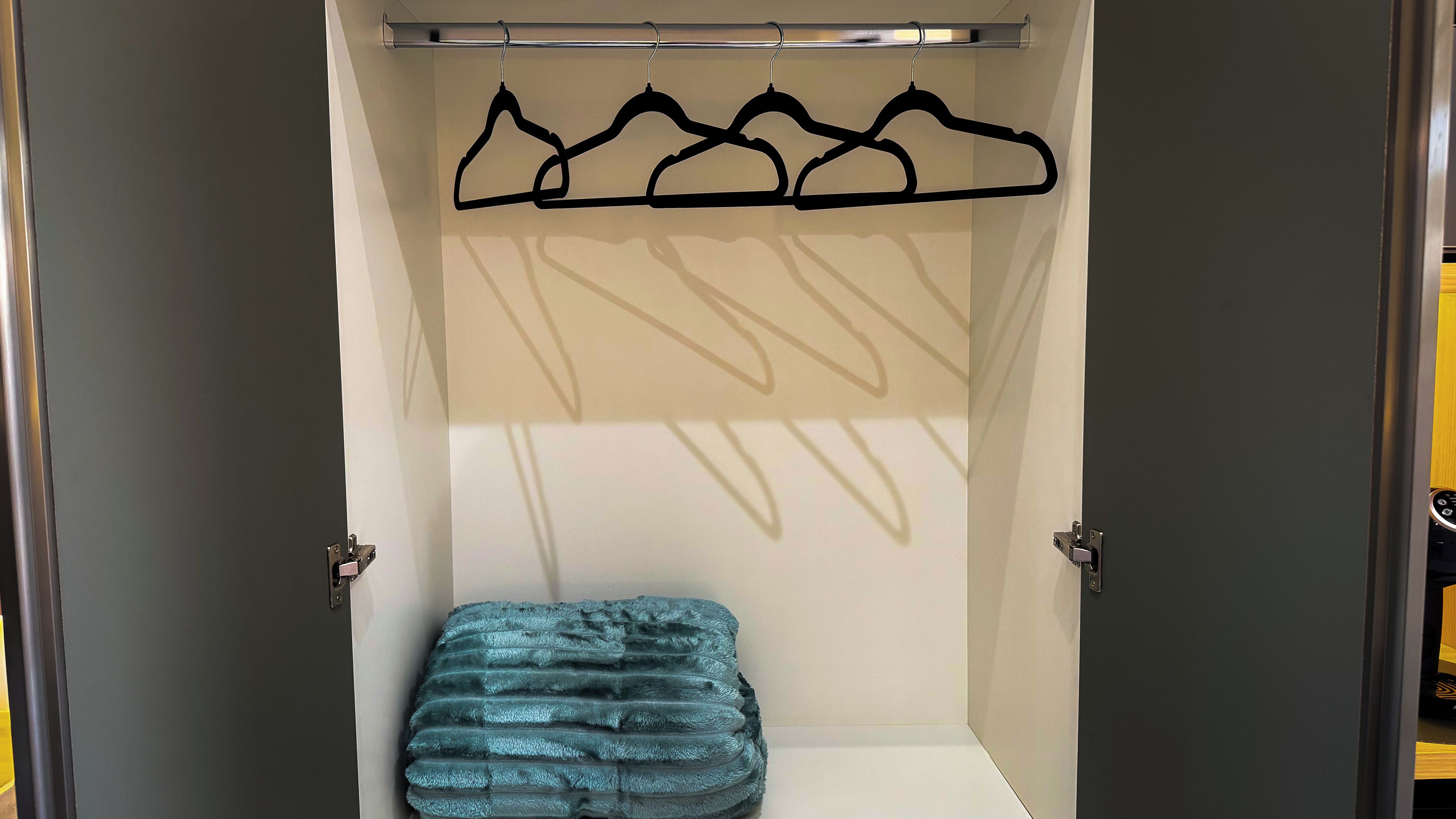 Um closet espaçoso com cabideiro e um banquinho.