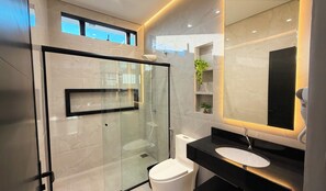 A modern bathroom with a glass-enclosed shower, a white toilet, a black countertop, and a large mirror. - Kaya Parque Sinop (Sinop)