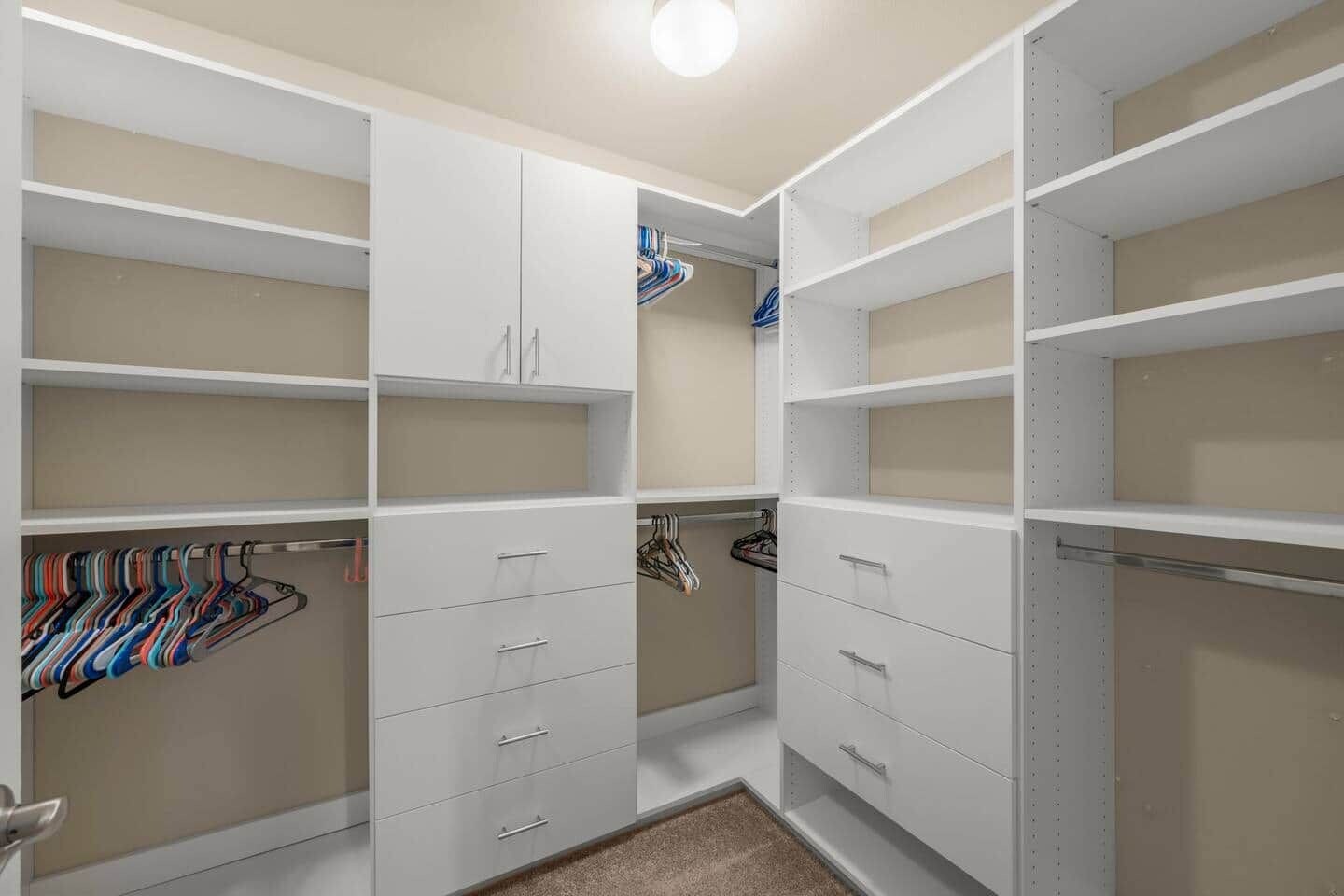Un vestidor con estantes abiertos, espacio para colgar ropa y cajones.