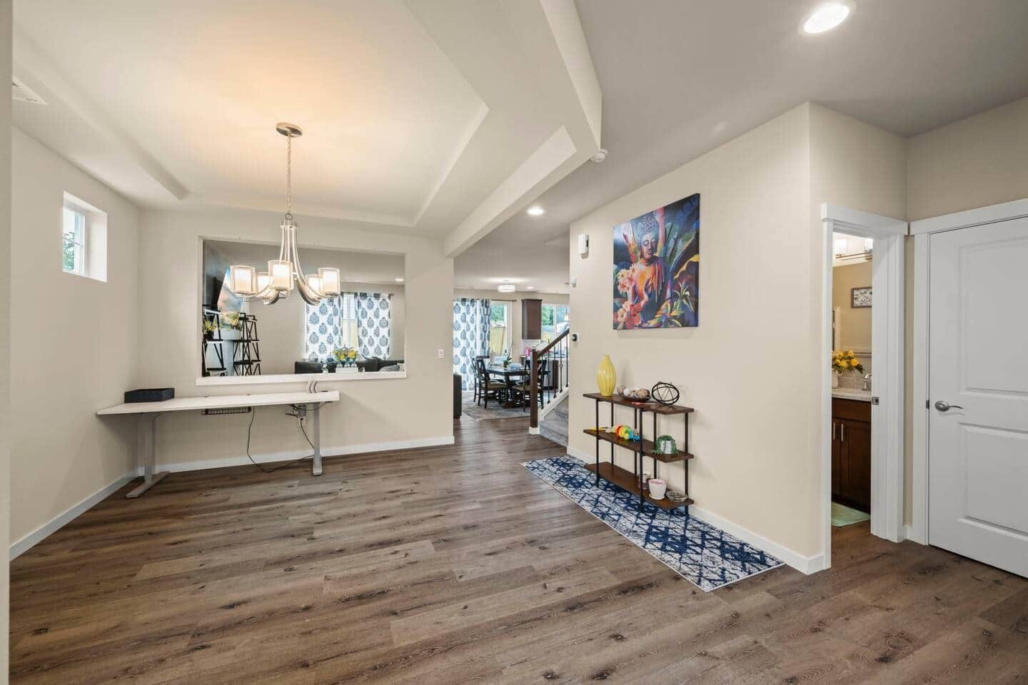 A spacious hallway with a dining area, a staircase, and a door leading to another room.
