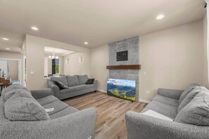 A living room with grey sofas, a flat-screen TV, and a fireplace.