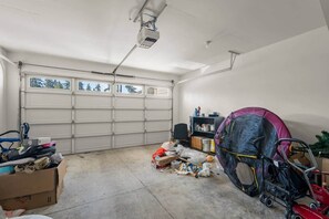 A garage with a large white door, a ceiling-mounted projector, and various items scattered on the floor.