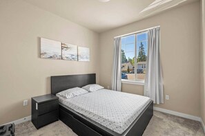 A bedroom with a bed, nightstand, and artwork on the wall.