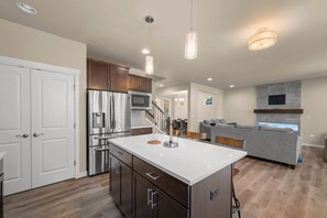 A modern kitchen with stainless steel appliances, a central island, and pendant lighting.