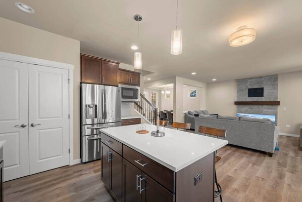 A modern kitchen with stainless steel appliances, a central island, and pendant lighting.