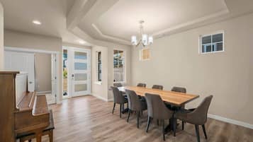 Een eethoek met een houten tafel en stoelen, een piano en een kroonluchter.