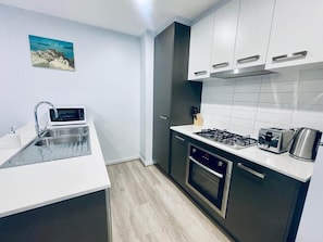 Cozinha compacta com pia, micro-ondas, fogão e forno.