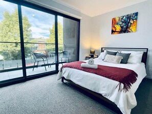 Quarto de hotel com uma grande porta de vidro deslizante que dá para uma área de estar externa.