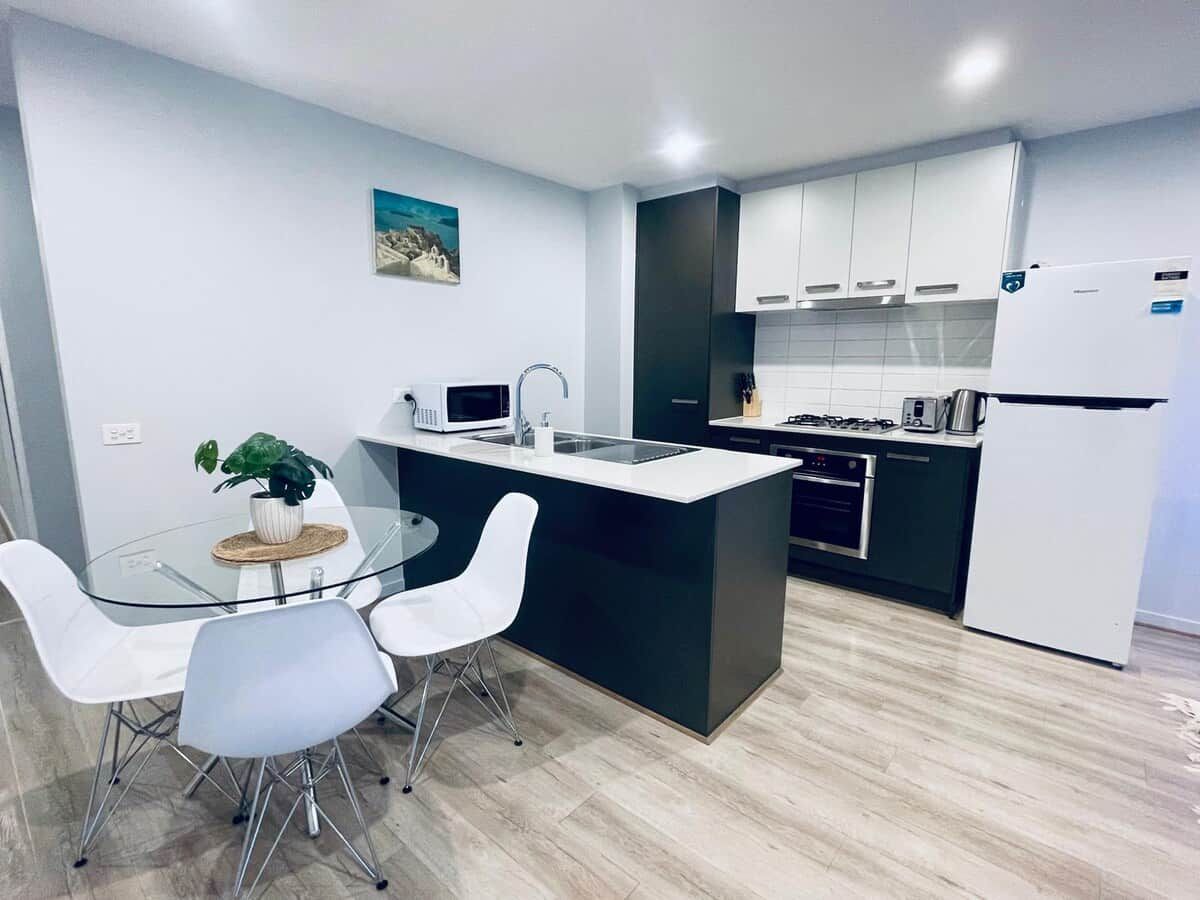 A modern kitchen with a central island, white cabinetry, and a stainless steel refrigerator.