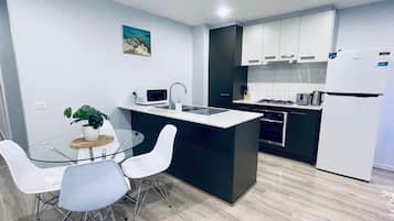 A modern kitchen with a central island, white cabinetry, and a stainless steel refrigerator.