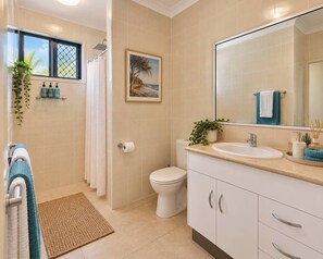 A bathroom with a toilet, sink, and shower area. - Bay Breeze - Tropical Escape Horseshoe Bay Bowen (Bowen)