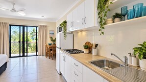 Uma cozinha moderna com armários brancos, uma pia de aço inoxidável e bancada de madeira.
